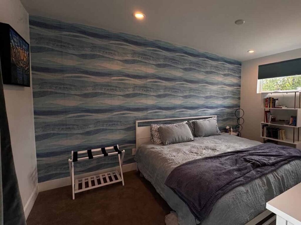 Bedroom wallpaper installation in Denver metro area with blue wave pattern accent wall behind bed