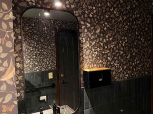 Restaurant bathroom wallpaper installation in Breckenridge Colorado with dark floral pattern and detailed wall coverage