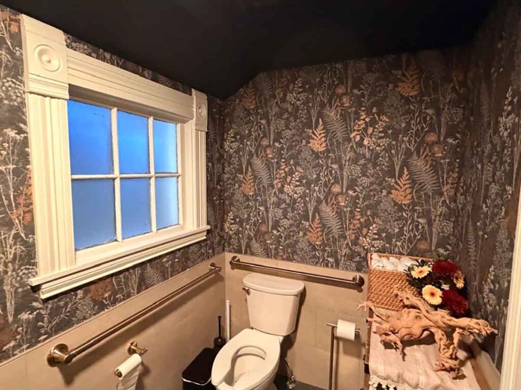 Bathroom wallpaper installation in Breckenridge Colorado with dark botanical pattern and precise corner alignment