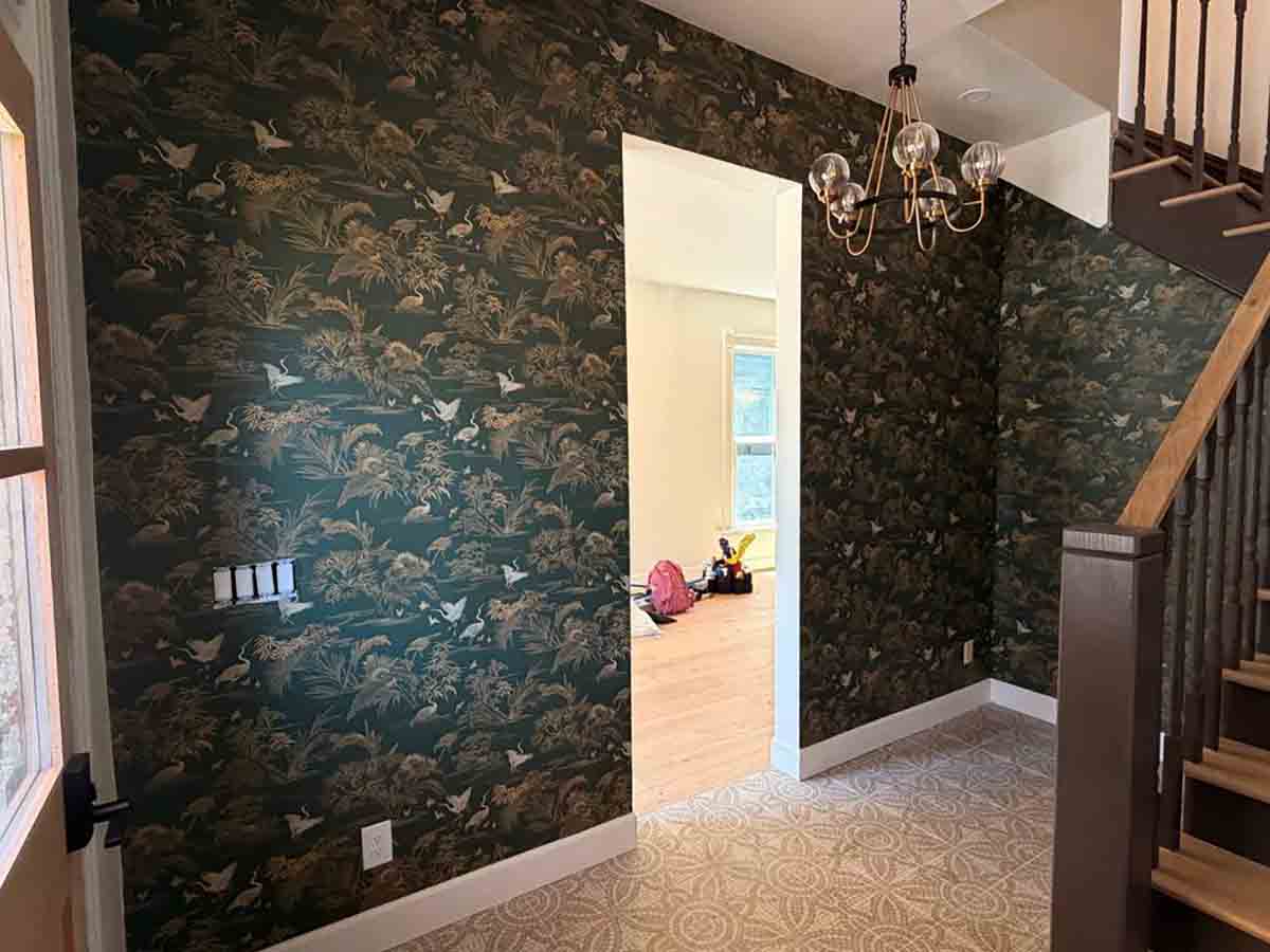 Professional wallpaper installation in Dillon, Colorado featuring a dark botanical wallpaper in a two-story entryway with seamless pattern matching.