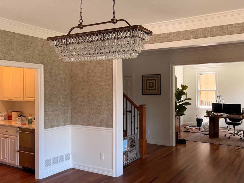 Professional grasscloth wallpaper installation in Firestone, Colorado featuring a textured natural wallcovering in a formal dining room with clean trimming around crown molding and wainscoting.
