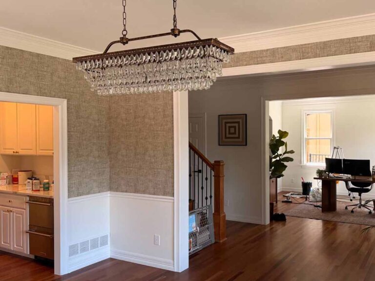 Professional grasscloth wallpaper installation in Firestone, Colorado featuring a textured natural wallcovering in a formal dining room with clean trimming around crown molding and wainscoting.