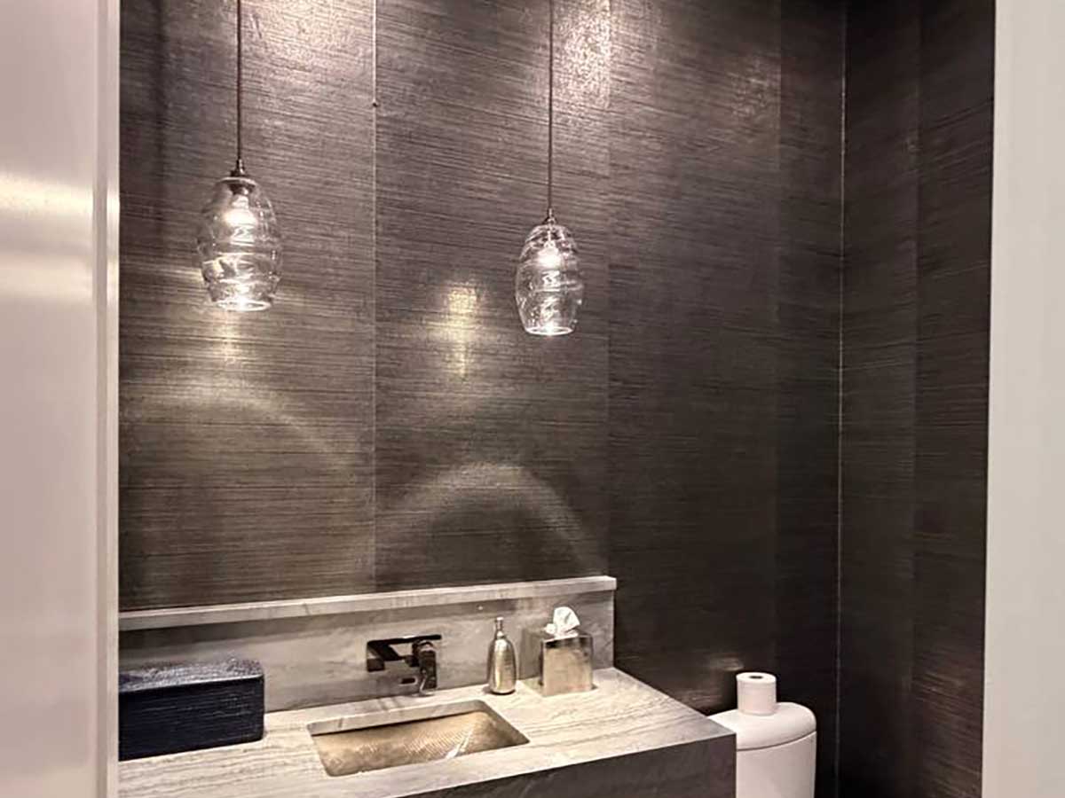 Professional grasscloth wallpaper installation in Georgetown, Colorado featuring a luxury powder room with dark textured wallcovering and a modern floating vanity.