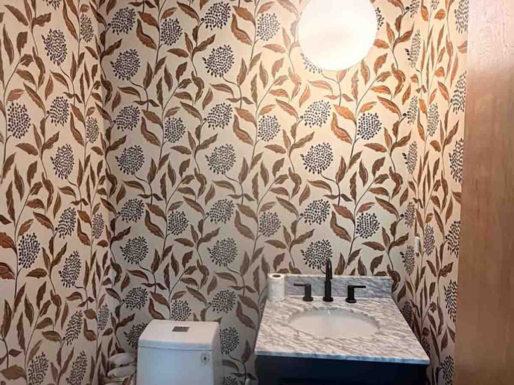 Powder room wallpaper installation in Greeley, Colorado featuring a modern botanical pattern with warm earth tones and precise seam alignment around the vanity and toilet.