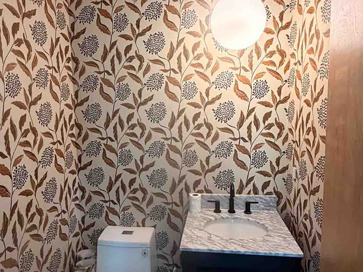 Powder room wallpaper installation in Greeley, Colorado featuring a modern botanical pattern with warm earth tones and precise seam alignment around the vanity and toilet.