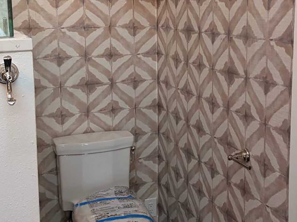 Bathroom wallpaper installation in Gypsum, Colorado featuring a geometric tile-inspired pattern with precise seam alignment around corners and plumbing fixtures.