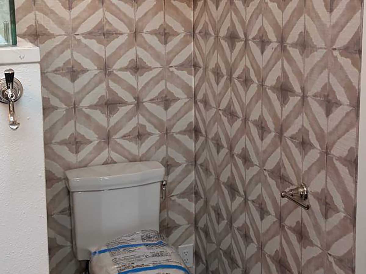 Bathroom wallpaper installation in Gypsum, Colorado featuring a geometric tile-inspired pattern with precise seam alignment around corners and plumbing fixtures.
