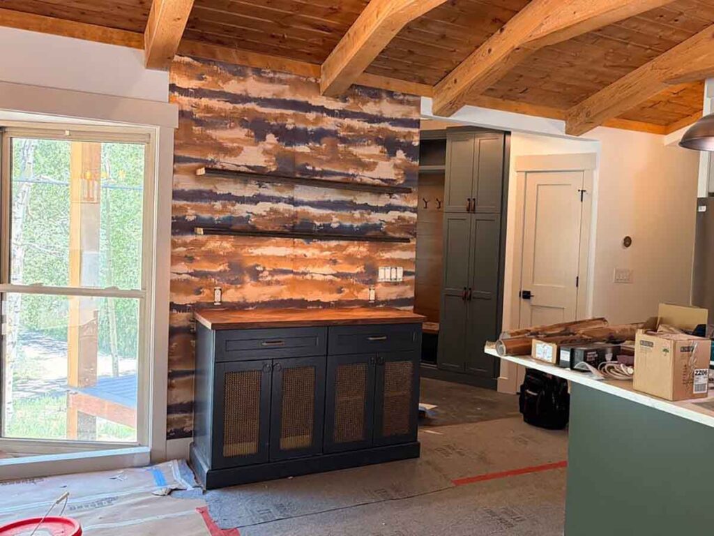 Rustic accent wall wallpaper installation in Johnstown, Colorado featuring a reclaimed wood design that complements exposed timber ceiling beams and custom built-in cabinetry.