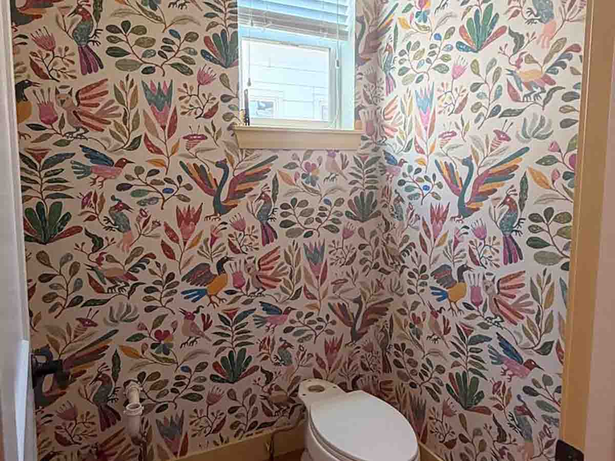 Powder room wallpaper installation in Lamar, Colorado featuring a colorful folk art botanical and bird pattern with seamless installation around a window and inside corners.
