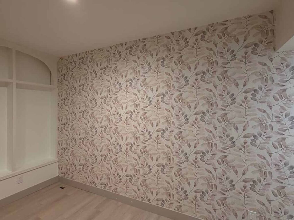 Accent wall wallpaper installation in Loveland, Colorado featuring a soft botanical leaf pattern in warm neutral tones, professionally installed with seamless pattern matching.