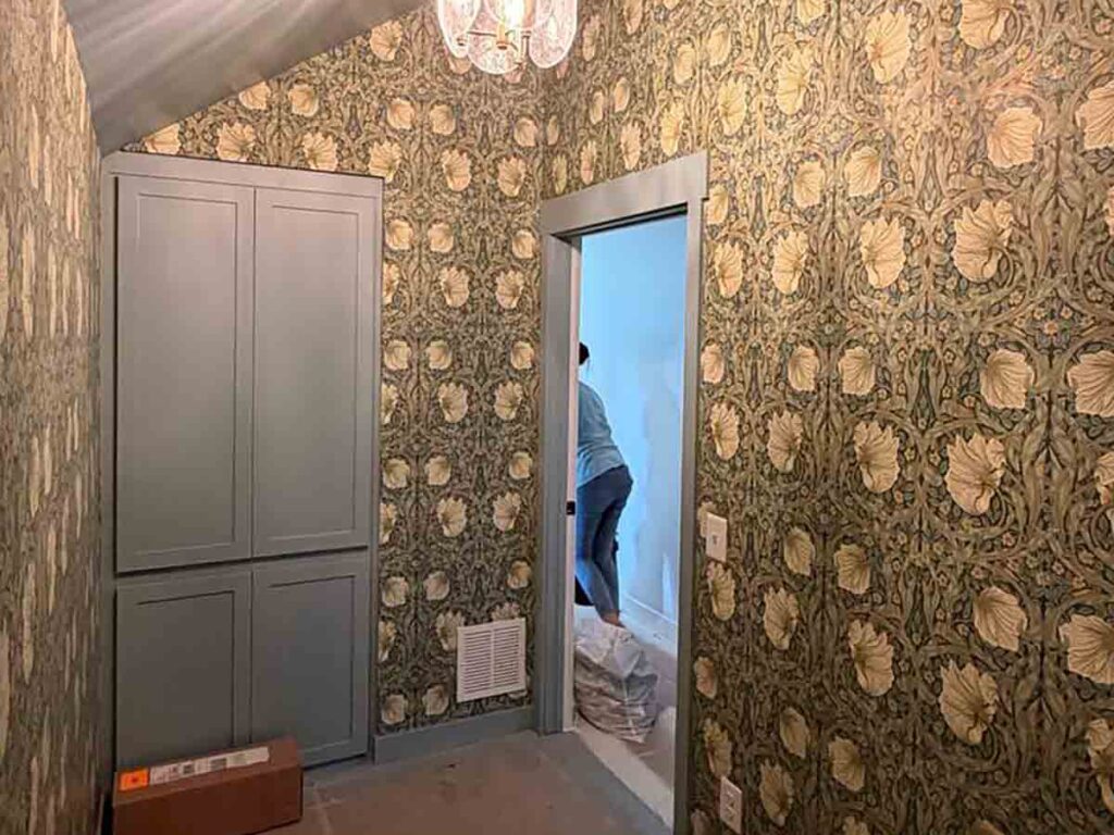 Wallpaper installation in a Manitou Springs, Colorado mudroom featuring a classic Arts & Crafts floral pattern on sloped walls with custom cabinetry and precise pattern alignment.