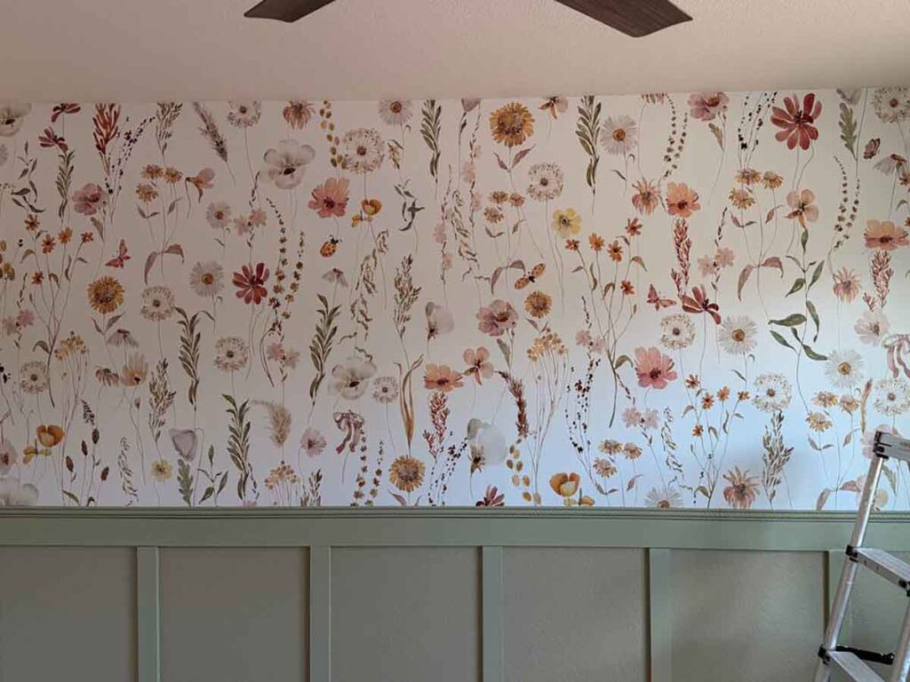Wildflower wallpaper accent wall professionally installed above sage green wainscoting in a bedroom in Nederland, Colorado, featuring soft botanical illustrations and seamless pattern matching.