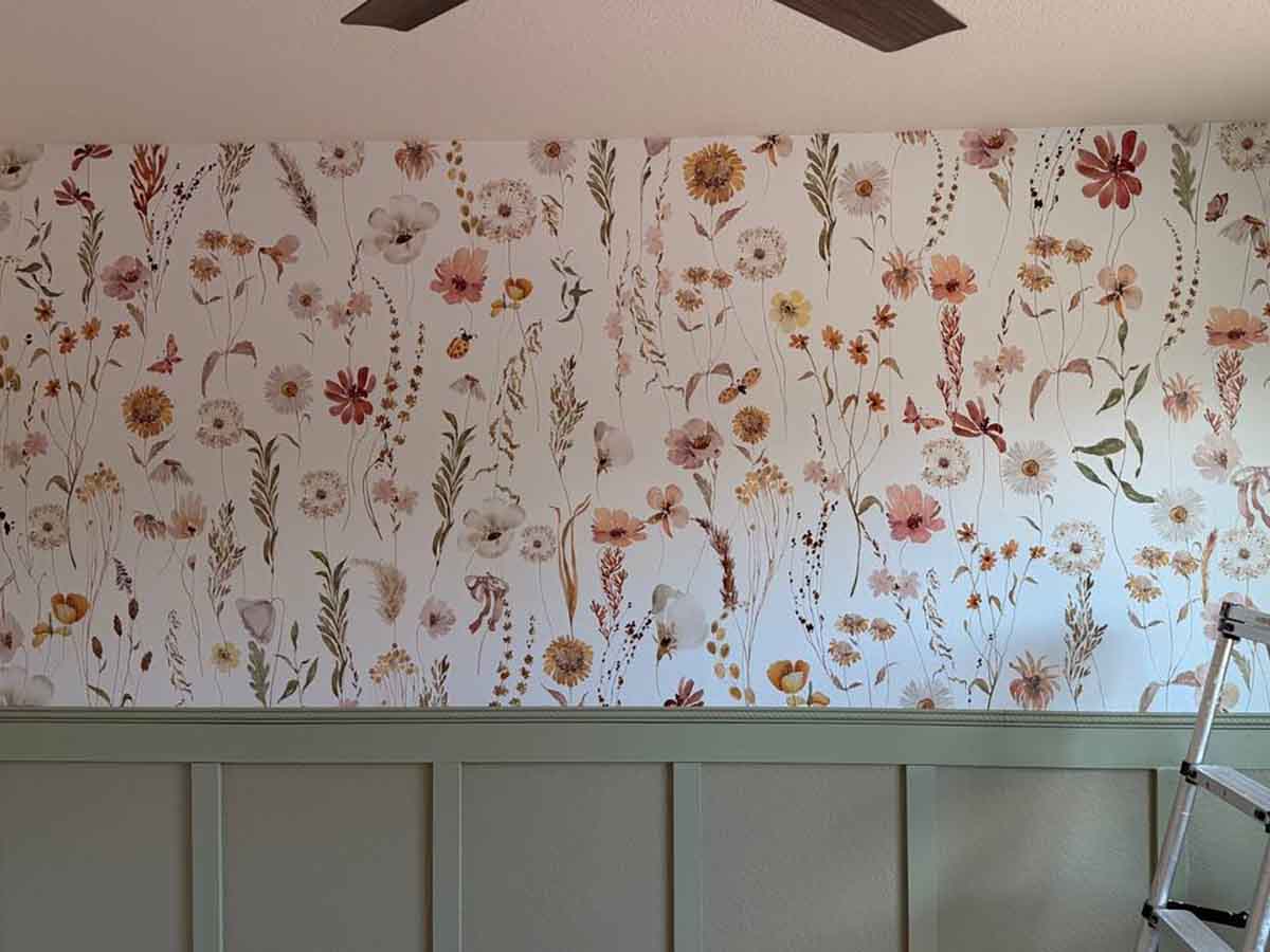 Wildflower wallpaper accent wall professionally installed above sage green wainscoting in a bedroom in Nederland, Colorado, featuring soft botanical illustrations and seamless pattern matching.