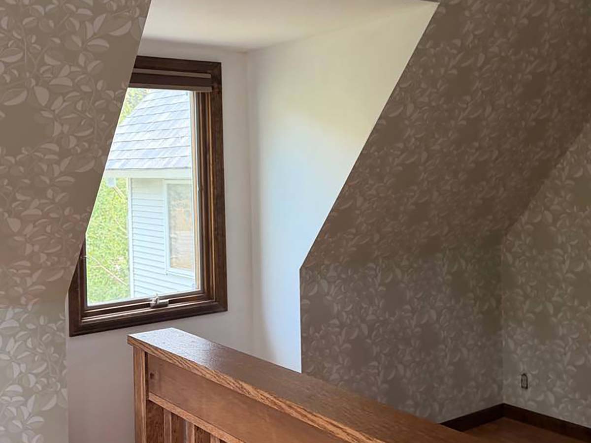 Wallpaper installation on sloped walls in a Pagosa Springs, Colorado home featuring a subtle botanical leaf pattern with precise alignment around angled ceilings and custom wood trim.